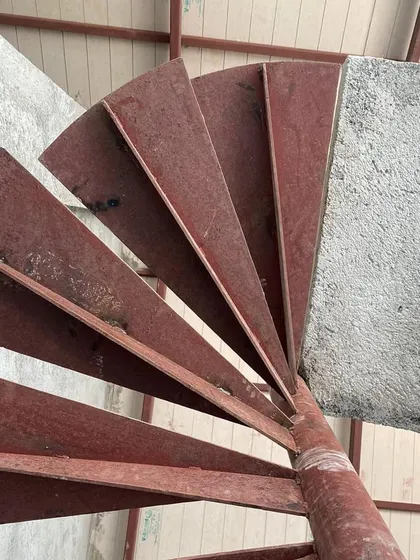 The raw steel spiral staircase at Ranch House, a sculptural element seen during the construction phase.