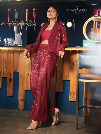 This red sequined two-piece set features wide-leg trousers and a matching jacket. It's a glamorous and modern take on a power suit, designed for parties and events.