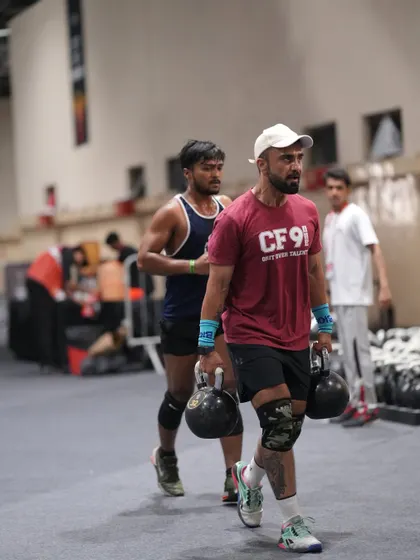 A farmer's carry with heavy kettlebells during a competition. This is a simple but brutal test of grip strength, core stability, and pure grit.