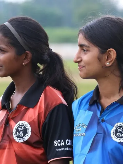 Two young female players, representing different teams, stand together, showcasing sportsmanship.