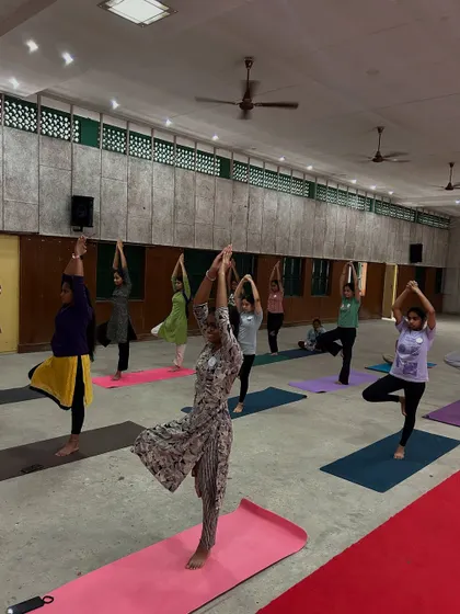 Young women at the Lila Poonawalla Foundation practicing Tree Pose (Vrikshasana). This balancing posture helps improve concentration and builds physical and mental stability.