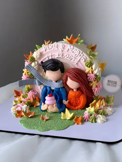 The perfect anniversary or Valentine's cake. This design features custom figurines of the couple surrounded by beautiful autumn leaves, creating a cozy and romantic scene.