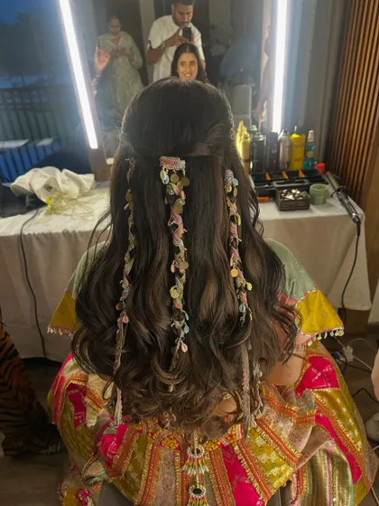 A unique and playful hairstyle featuring soft waves and delicate, colorful ribbons woven into small braids for a festive Mehendi look.