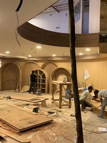 A wide shot of the school project site, with carpenters working on various elements. The entire space is a testament to the versatility of plywood as a building material.