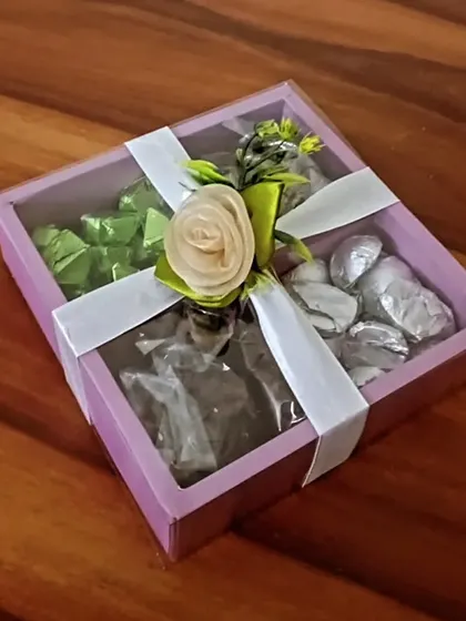 A still shot of the 'Crunchy Munchy Box', elegantly tied with a white ribbon and a floral decoration. It's a perfect treat for yourself or as a gift.
