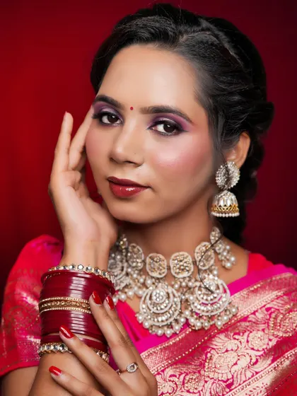 A beautiful traditional look in a bright pink saree. The makeup features shimmery purple eyeshadow and is paired with heavy, ornate silver jewellery.