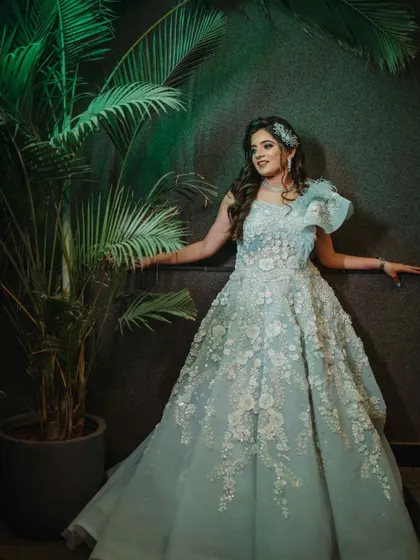 A full-length shot of the bride against a dark background. Her powder blue gown and radiant makeup create a stunning contrast.