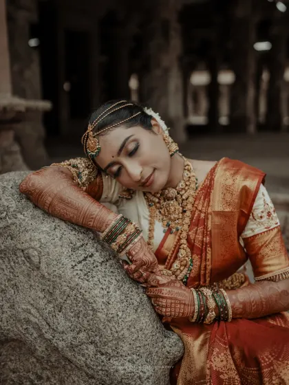 A serene close-up of the bride, her traditional attire and jewelry shining against the ancient stone.