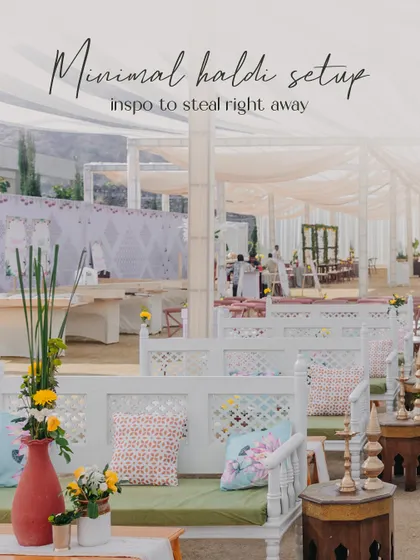 A chic and minimal Haldi seating area with white wooden benches, patterned cushions, and simple floral arrangements. This shows my ability to create understated yet beautiful event designs.