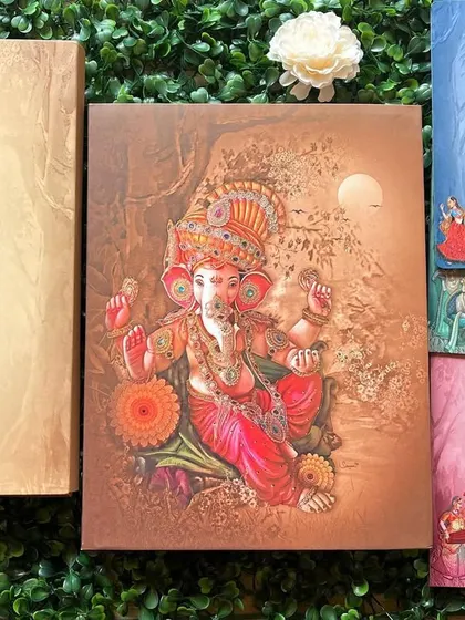 A stunning invitation featuring a 3D embossed illustration of Lord Ganesha. The set includes multiple inserts in different colors for various wedding functions.
