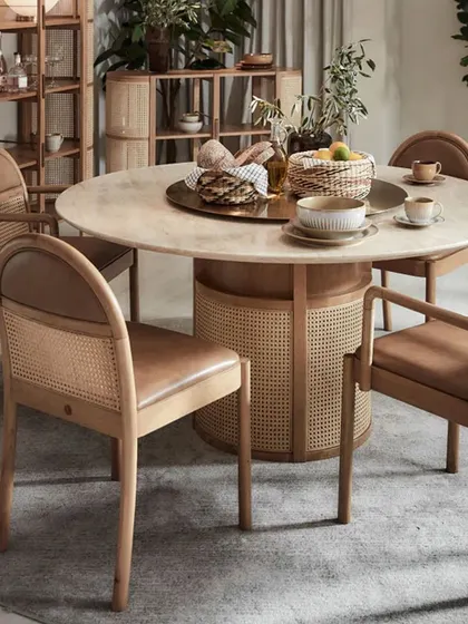 The complete Siena Dining Set, a perfect centerpiece for a refined dining space. The solid oak frames of the chairs, combined with natural rattan and leather, complement the magnificent travertine stone table.