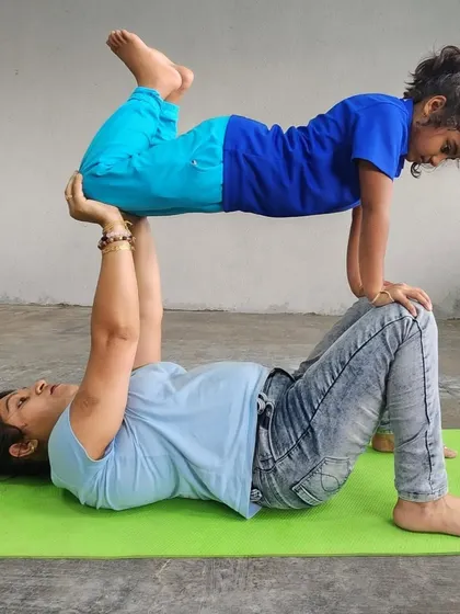 A coach or senior camper helps a younger child experience the "flying" pose, showing our commitment to mentorship and safety.