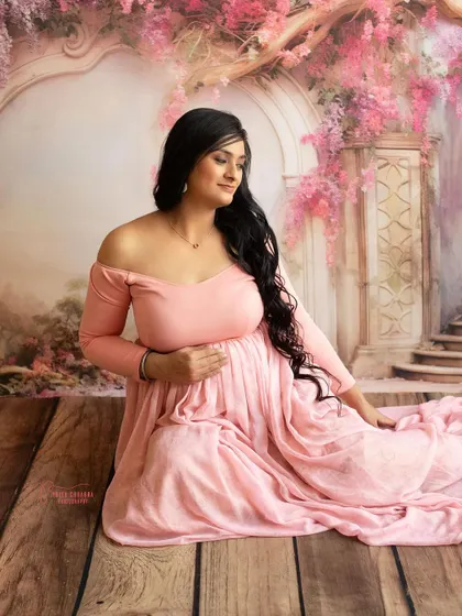 A dreamy, painterly portrait. The soft pink tones of the dress and the romantic backdrop create a scene straight out of a storybook.