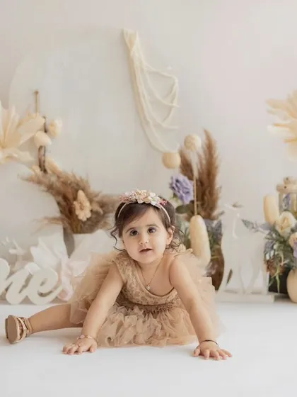 A beautiful portrait before the cake smash. This one-year-old is ready for her party in a lovely boho-themed setup with dried flowers and pampas grass.