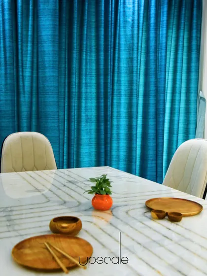 A closer look at the dining table, where the subtle gold inlay pattern on the white marble contrasts beautifully with the vibrant blue curtain wall.