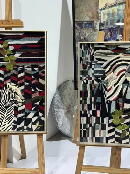 The pair of embroidered tapestries, "Tigress in her Jungle" and "Horse in his Amber Field," displayed side-by-side. This image shows how the two distinct pieces complement each other in style and theme.