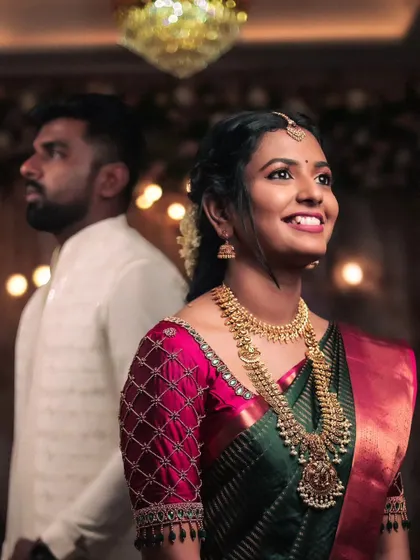 The bride's radiant smile is the highlight of this portrait. With the groom slightly out of focus in the background, this shot beautifully captures her happiness and anticipation on their special day.