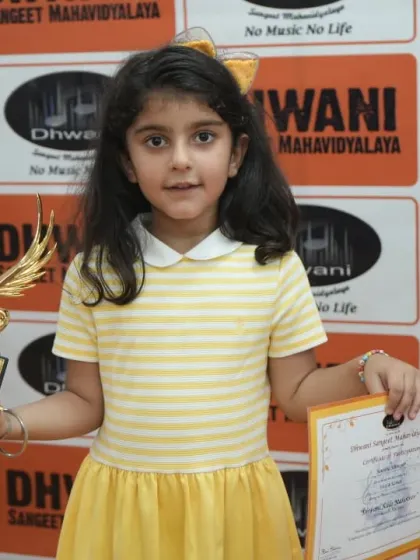 A young girl proudly holds her certificate and trophy.