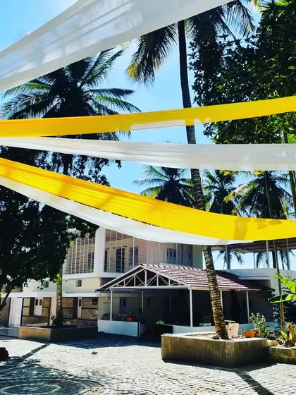I used simple, flowing drapes of yellow and white fabric to create a festive canopy for this outdoor haldi event. The drapes are set against the natural backdrop of palm trees and a clear blue sky.