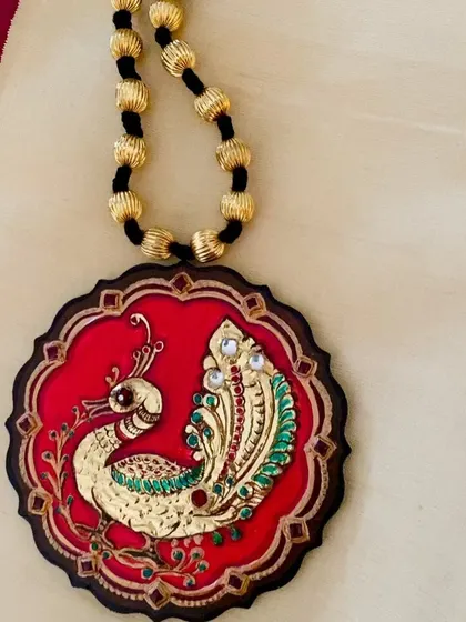 Another angle of the red peacock pendant, showcasing its scalloped edges and the craftsmanship of the gold leaf application.