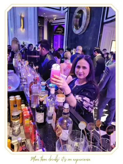 A guest poses with her beautifully crafted pink cocktail, with the bustling bar in the background. We love capturing these moments of pure enjoyment.