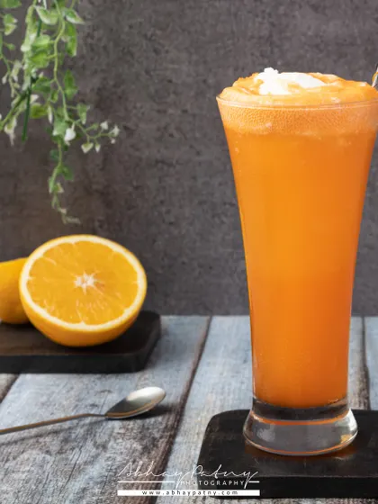 A tall glass of fresh orange juice. The setup is simple and clean, letting the vibrant, natural color of the juice speak for itself.