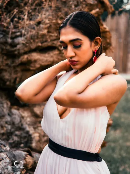A soft and introspective moment. Her pose is graceful, and the natural setting adds a sense of peace and tranquility.