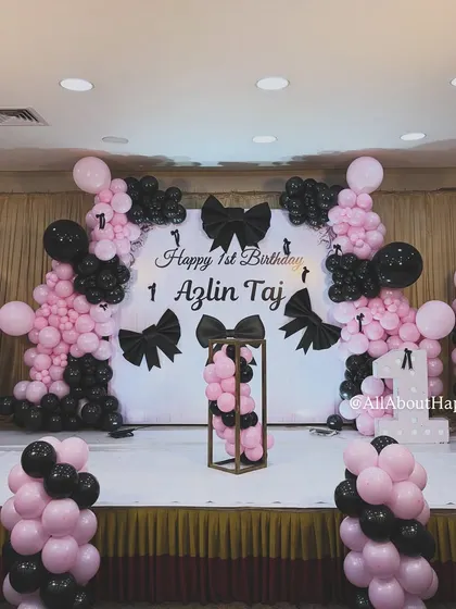 Another angle of the sophisticated bow-themed decor, showing the symmetrical balloon columns and the central display stand, perfect for the birthday cake.
