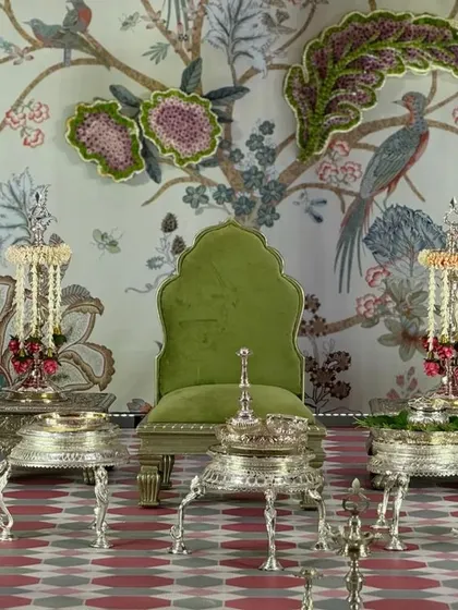The 'Janavasam' ceremony setup, featuring silver seating and traditional lamps against a stunning 'Tree of Life' backdrop. The design blends rich textures and handcrafted details to honor this important Tamil ritual.