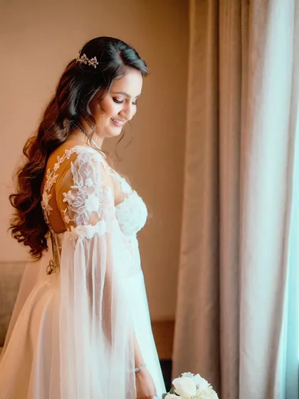 A side profile showcasing the beautiful details of her gown's sleeves and her elegant, wavy hairstyle.