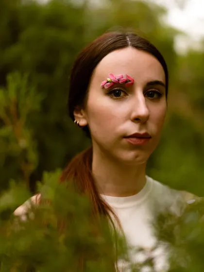 A slightly wider shot from the same series, using the foliage as a natural frame. This technique adds depth and context to the creative portrait.