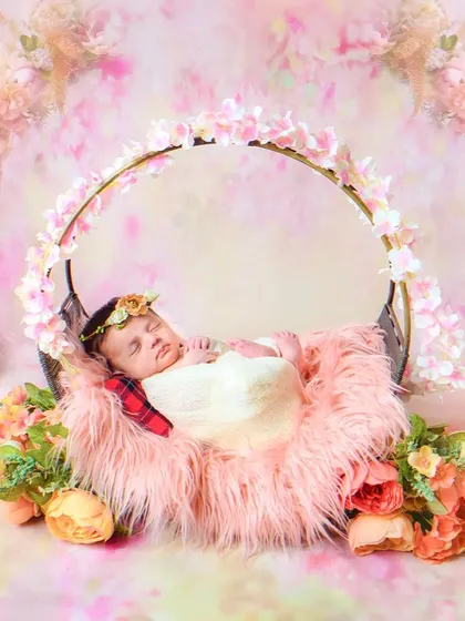 A wide shot of a newborn sleeping in a floral swing, creating a beautiful and serene scene. The entire setup is designed to be a work of art.