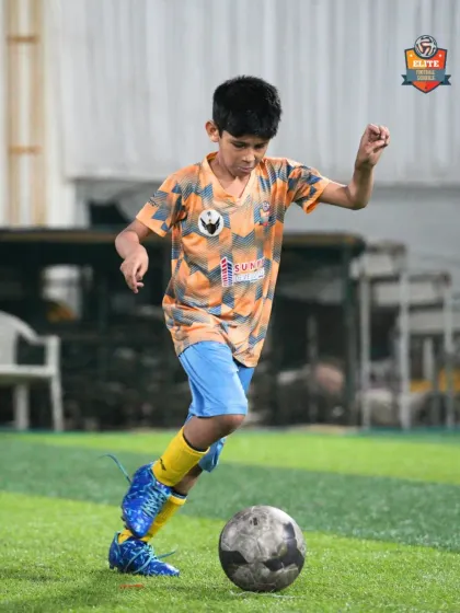 A young player dribbles with his head up, looking for a teammate to pass to.