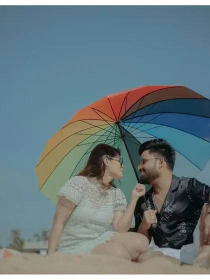 A playful and colorful shot of the couple under a rainbow umbrella on the beach. This image is full of fun, personality, and the vibrant joy of their love.