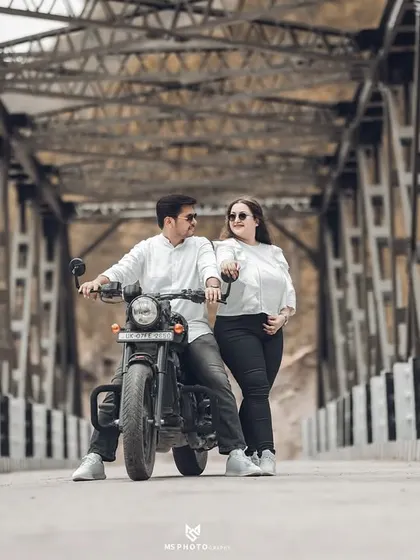 Another fun, candid shot on the bridge. The couple's interaction with the bike adds a story-telling element to their pre-wedding photography.
