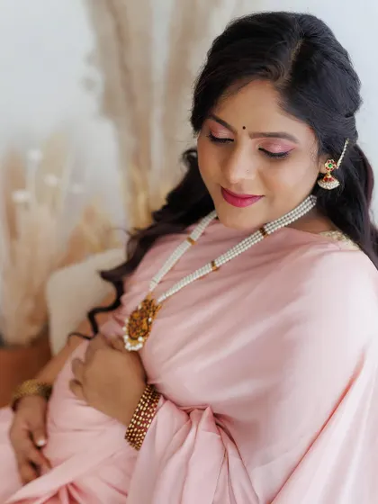 A close-up on the soft, romantic makeup for a maternity shoot. The pink eyeshadow and lipstick perfectly match the client's pastel pink saree, creating a harmonious and pretty look.