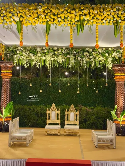 A detailed shot of the couple's seating within the mandap, framed by hanging bells and a beautiful floral canopy.
