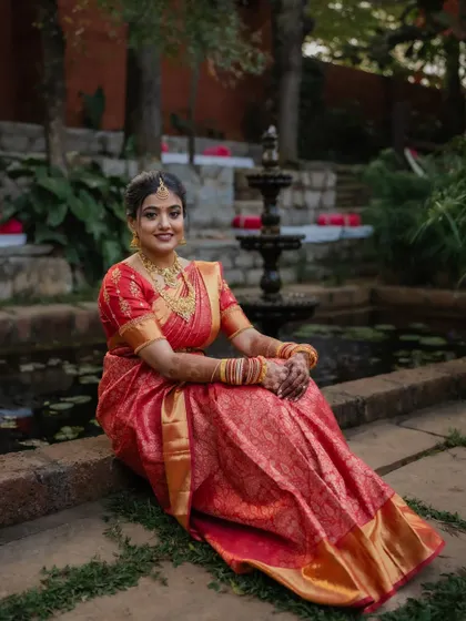A portrait of the bride in her stunning red saree, framed by the rustic charm of her wedding venue. We focus on creating images that are both beautiful and full of character.