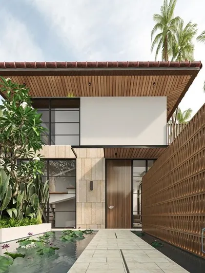 The entrance to one of the Guirim villas, showcasing a pathway over a lily pond leading to the front door. A terracotta jali screen provides privacy while adding a traditional, handcrafted element to the contemporary design.