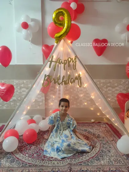 The birthday girl enjoying her special tent setup, complete with a number '9' foil balloon.