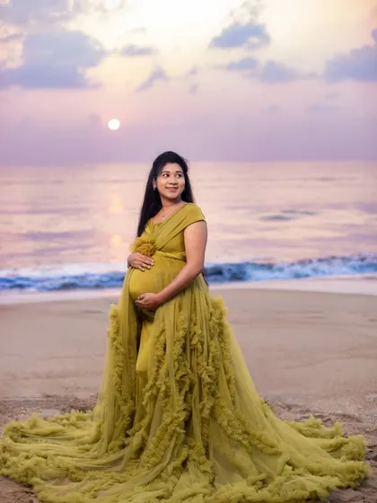 A serene and majestic portrait against a pastel-colored sky. The beach provides a stunning natural canvas for maternity art.