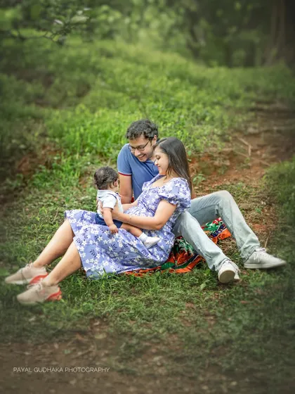 A young family sits together on a blanket in a grassy field, enjoying a peaceful moment with their baby. This wide shot establishes the serene and natural environment of my outdoor photoshoots.