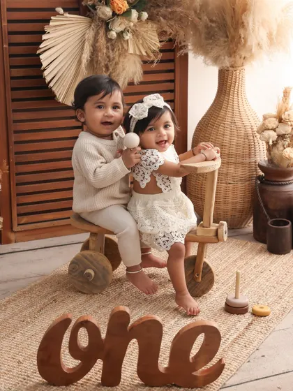 A playful moment with the twins on a wooden tricycle. This milestone shoot is filled with fun props that allow the children's personalities to shine through.