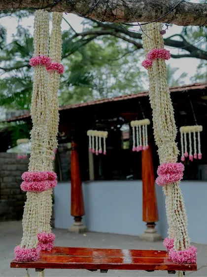 A swing decorated with jasmine and pink flowers for a naming ceremony.