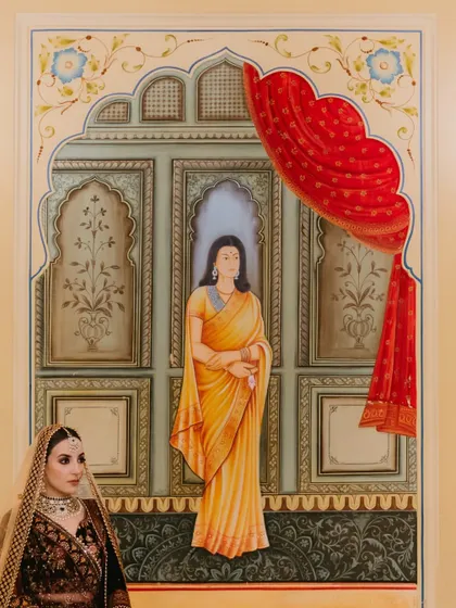 A creative portrait where the bride stands beside a traditional Indian wall painting, creating a beautiful blend of art and reality.