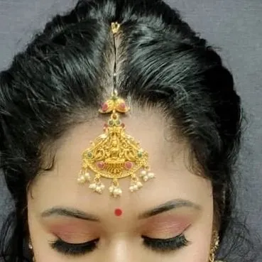 A detailed close-up of the eye makeup and traditional temple-style maang tikka, showcasing the precision taught in our classes.