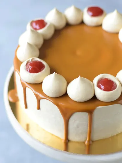 A close-up of the Strawberry Biscoff cake, showing the glossy Biscoff drip and the creamy meringue kisses filled with strawberry compote. It's a feast for the eyes and the palate.
