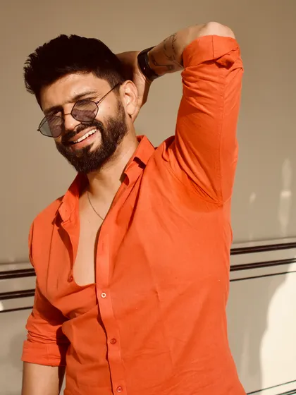 A happy, sun-kissed shot. The bright orange shirt is a bold choice that exudes confidence.