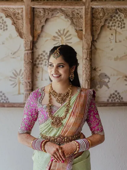 This bride looks radiant for her wedding day. The soft glam makeup with a hint of color on the lips perfectly complements her beautiful pastel green and pink silk saree.
