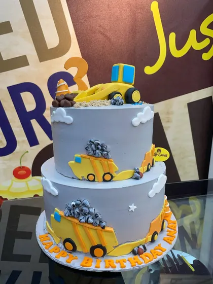 A 3kg two-tiered construction theme cake with fondant dump trucks, perfect for a little builder.